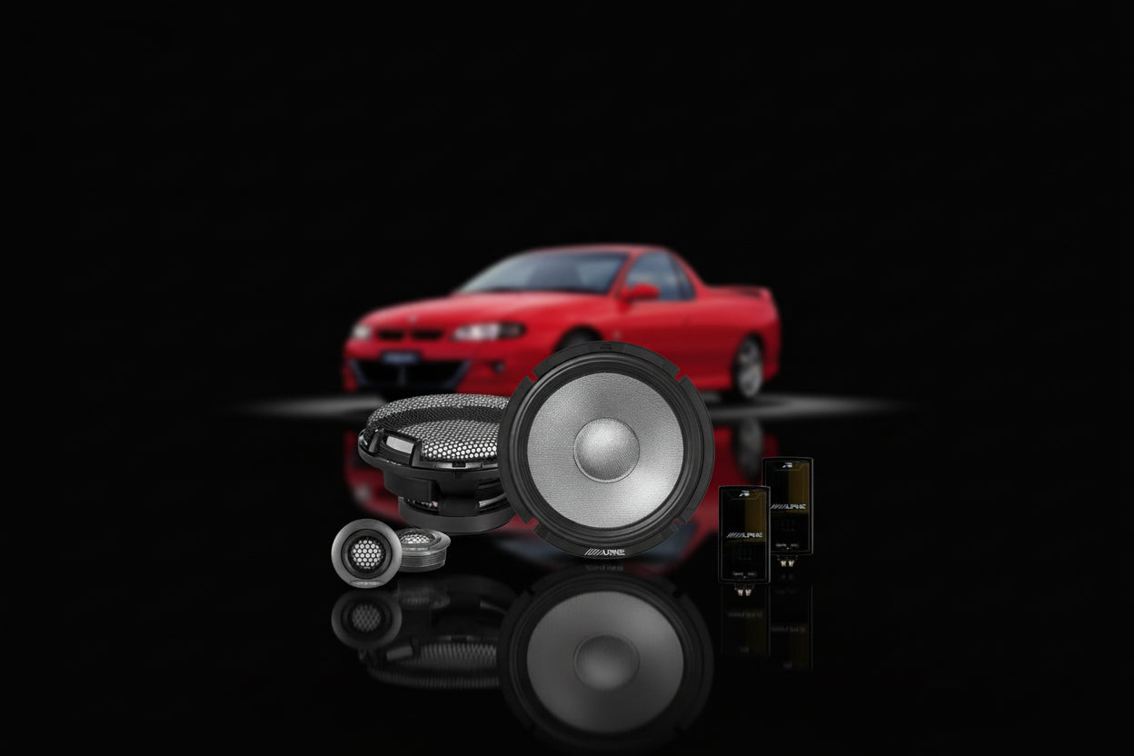 Red car on a black background with car audio components in the foreground.